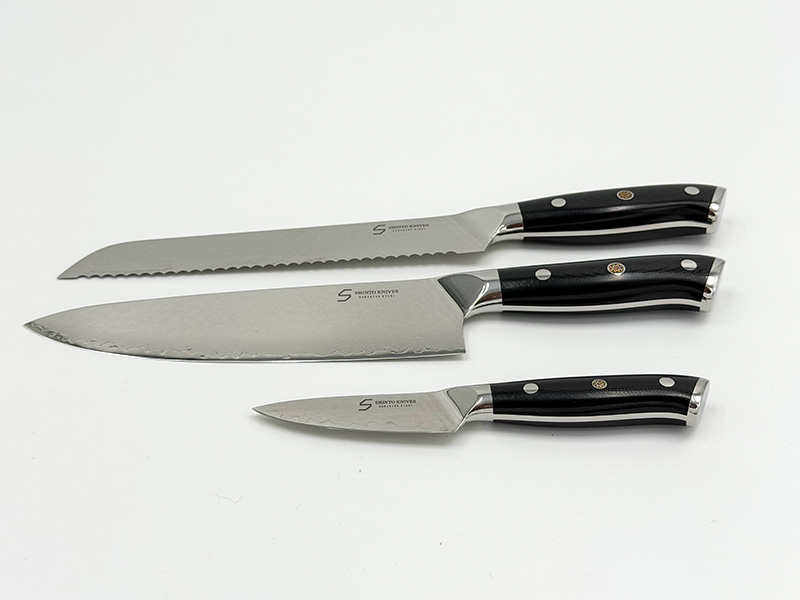 Shinto knivsæt i damaskusstål med kokkekniv, brødkniv og urtekniv på køkkenbord