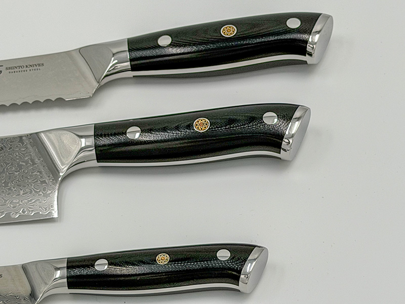 Shinto knivsæt i damaskusstål med kokkekniv, brødkniv og urtekniv på køkkenbord