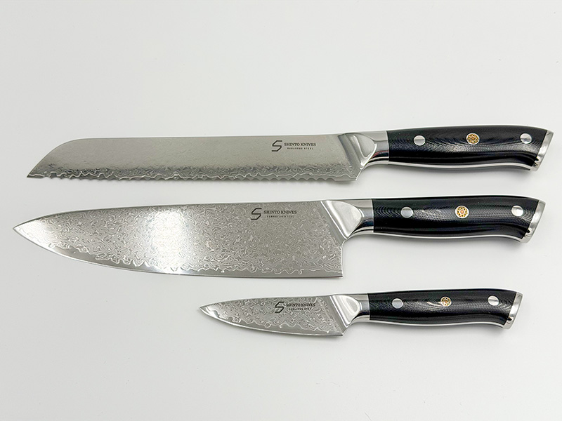 Shinto knivsæt i damaskusstål med kokkekniv, brødkniv og urtekniv på køkkenbord